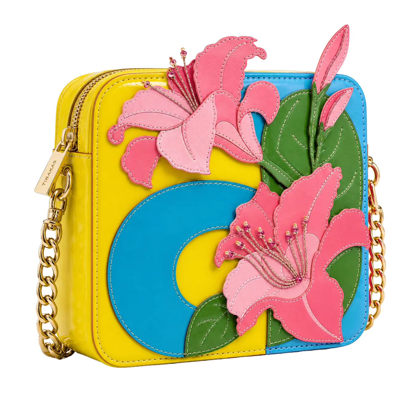 A structured colorblock patent leather crossbody bag in yellow and blue, featuring 3D leather pink lily appliqués, green leaves, and gold-tone chain straps with a "Tirakas" zipper pull.