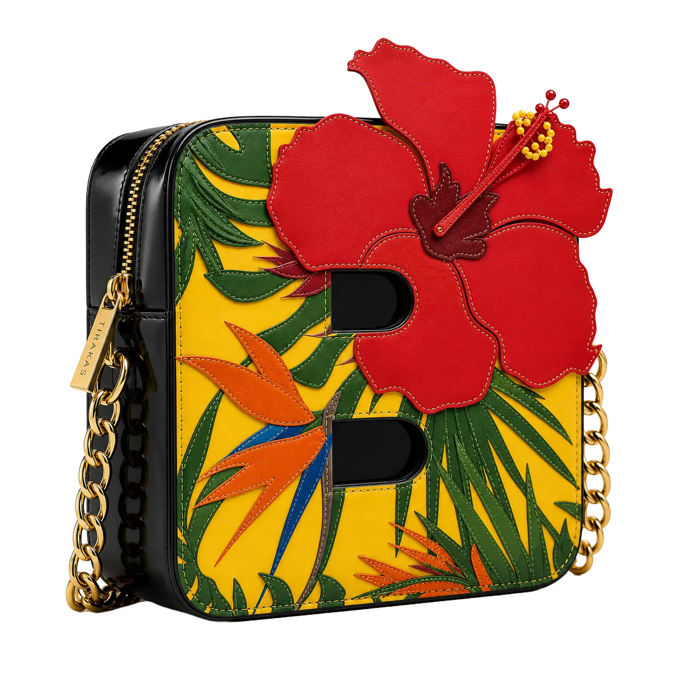 A structured patent leather crossbody bag in black and yellow featuring a stylized letter "B" profile, a large 3D red hibiscus flower appliqué, green foliage, orange bird-of-paradise accents, and gold-tone chain straps.