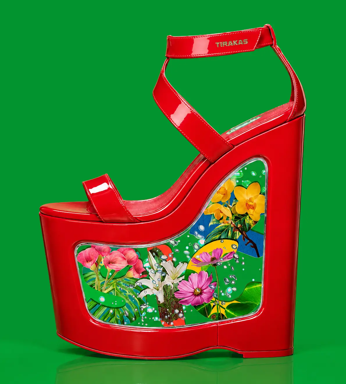 A glossy red patent leather platform high heel featuring a clear resin wedge window filled with botanical "SICK" letter graphics and vibrant flowers, set against a solid green background.